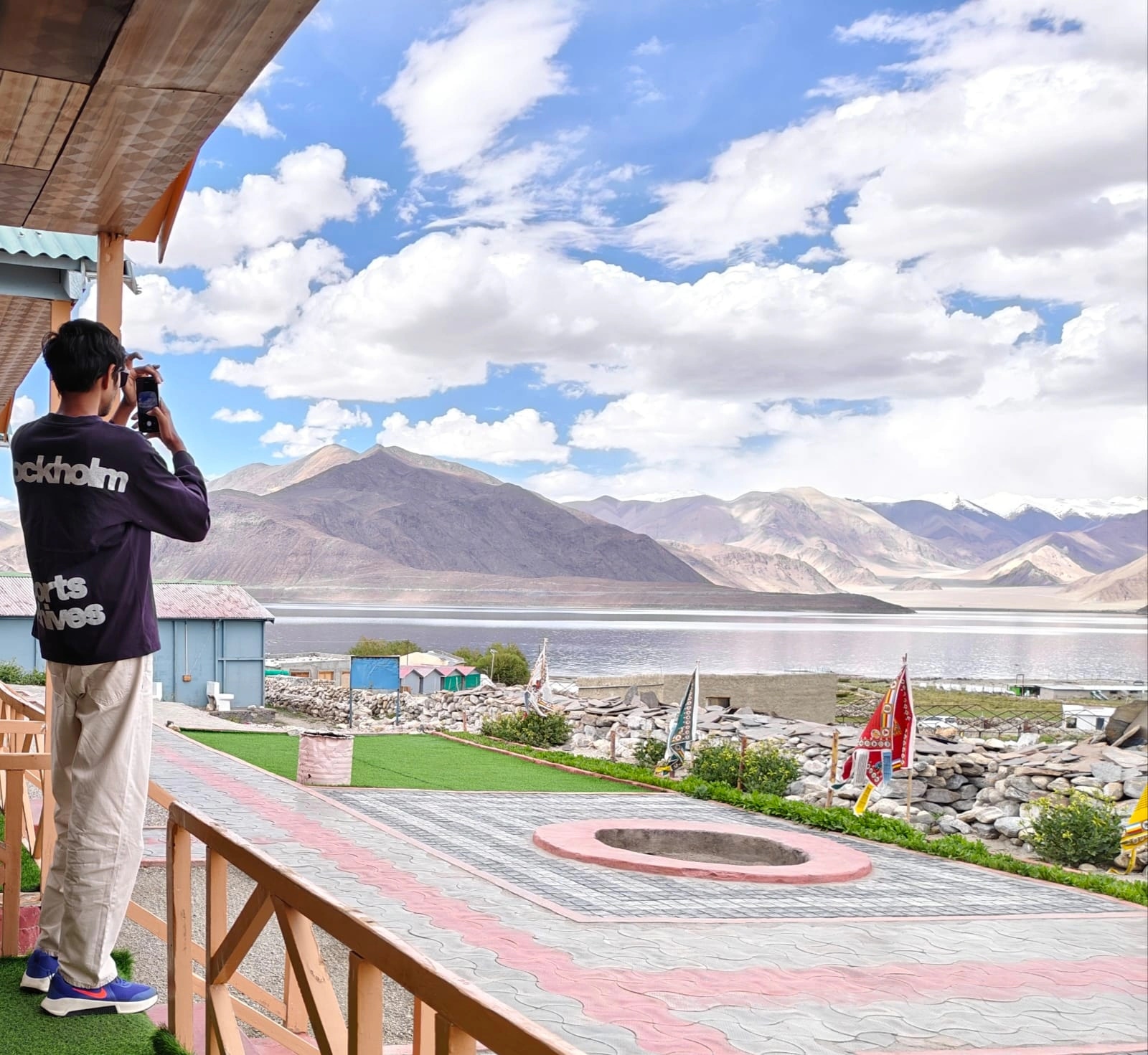 A traveller photographing the Ladakh mountain and lake landscape.